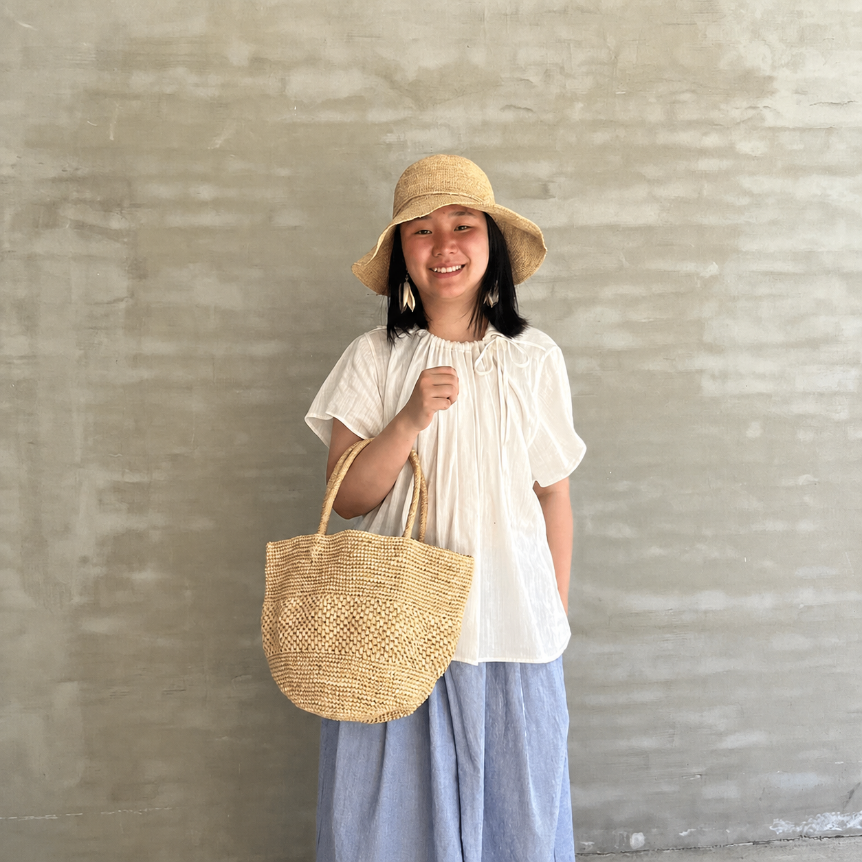 Tiger Canada artisan carrying a natural handwoven raffia tote